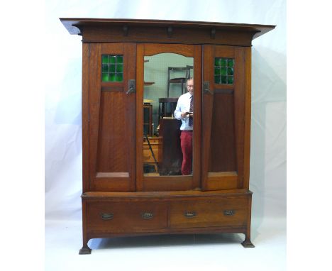 A fine quality British Arts & Crafts medium oak twin door wardrobePossibly Scottish, the twin doors having green glass panels