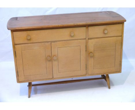 An Ercol light elm and beech sideboard Circa 1950's, having two drawers above three cupboard doors, raised tapering column su