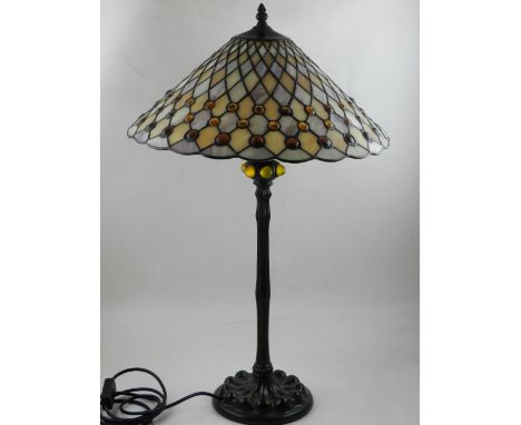 A Tiffany style table lamp, having leaded coloured glass shade, raised on a shaped cast metal base, H. 59cm 