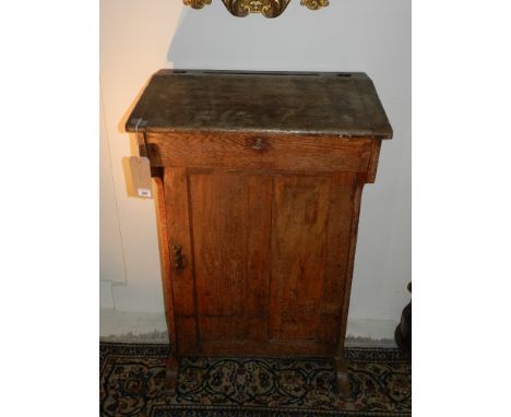 An early 19th century oak clerks desk, having desk top above a cupboard door. H: 107cm W: 68cm