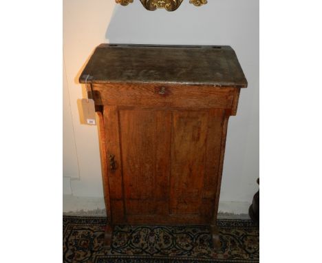 An early 19th century oak clerks desk, having desk top above a cupboard door. H: 107cm W: 68cm