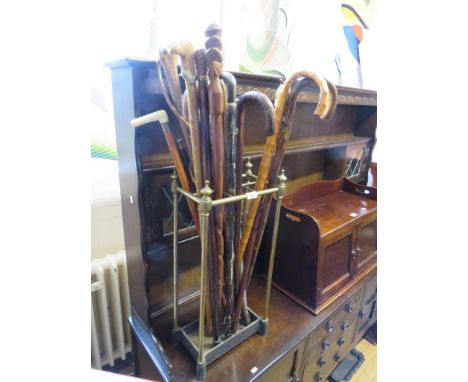 A vintage brass stick stand together with a quantity of walking sticks 