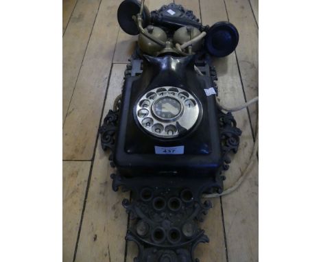 A vintage telephone with pierced cast metal decorative wall mounting back 