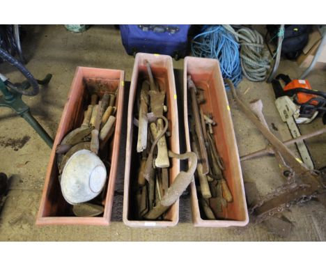 Three plastic plant troughs and contents of various vintage tools to include hand scythes, shoe last, slashers, hoe head atta
