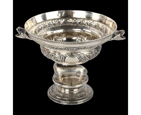 An Antique Continental silver pedestal bowl, with ewe support, grotesque mask handles and relief embossed foliate decoration,