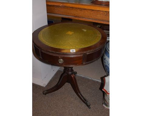 A reproduction mahogany circular occasional table, fitted three frieze drawers above tripod legs terminating in brass castors