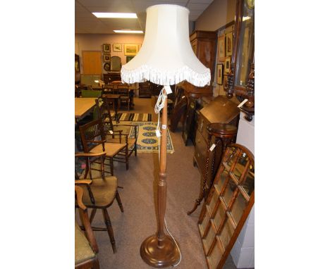 A stained wood standard lamp with cream coloured shade.