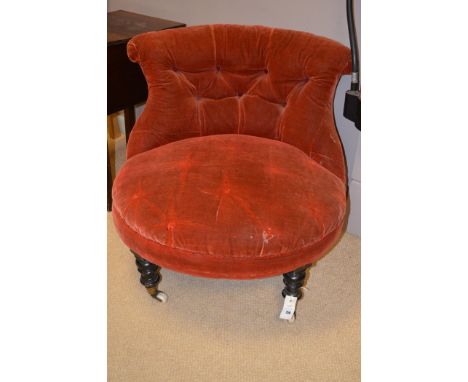 A Victorian button back easy chair upholstered in red velour, raised on turned ebonised legs terminating in ceramic castors.
