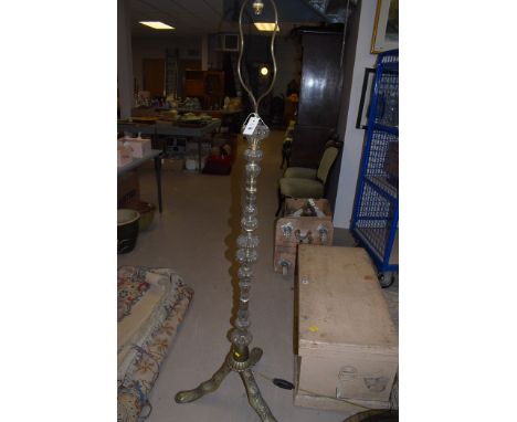 A moulded glass and brass standard lamp, raised on tripod feet.