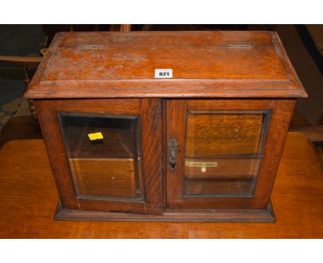 An early 20th Century oak smoker's cabinet, the bevelled glass doors opening to reveal drawers and shelving; and a needlework