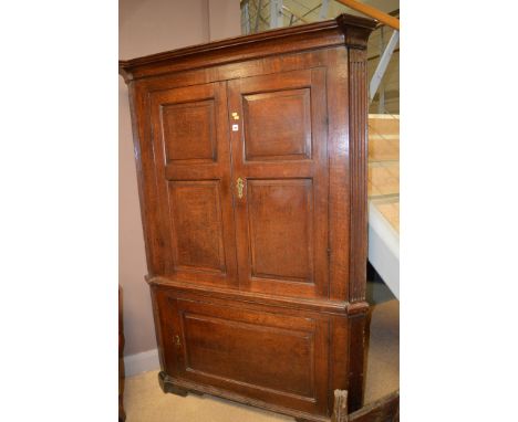 An early 19th Century floor standing oak corner cupboard opening to reveal shelving, above a single panel door fitted a singl