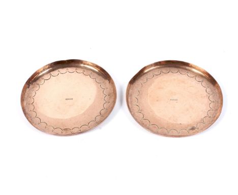Two Newlyn Arts and Crafts copper coasters, circa 1900. Stamped uppercase marks, each engraved with a berried swag border, 11