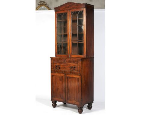 An early 19th century mahogany glazed bookcase. With architectural pediment above twin arched astragal glazed doors and three