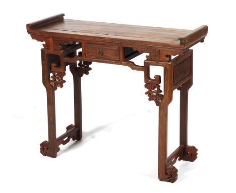 A Chinese hardwood altar table. The rectangular top with scroll ends, above a frieze drawer flanked by pierced fretwork key p