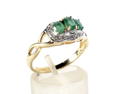 A modern 9ct gold, emerald and diamond dress ring. The three light-green, graduated oval mixed-cut emeralds claw set within a