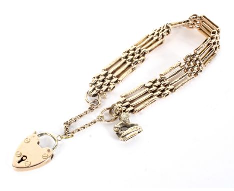 A vintage gold part-textured four-bar 'gate' bracelet on a padlock clasp. Hung with a single 'lion' fob charm (unmarked), the
