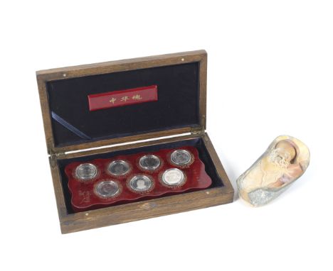 A cased set of 1990/2000s Chinese commemorative coins and a small carved soapstone boulder. The coin set commemorating celebr