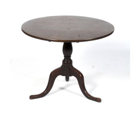 A Georgian circular oak tilt top tripod table raised on a baluster column to outswept cabriole supports. Diam 75cm.