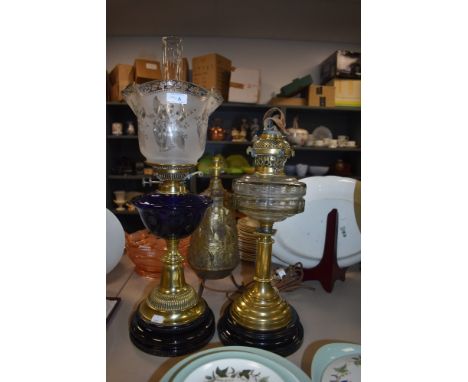 Two brass based oil lamps one with blue glass well complete with shade and chimney the other clear glass well no chimney or s