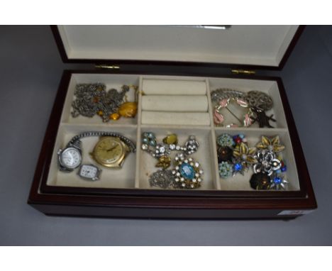 A wood effect jewellery case containing a selection of costume jewellery including clip earrings, brooches, Timex automatic w