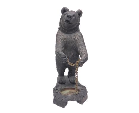 A Black Forest style composition umbrella stand, modelled in the form of a standing bear holding a chain, the shaped carved w