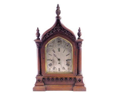 A Victorian gothic mantel clock, the oak case decorated with scrolls, pillars, and leaf carved finials, the arched dial with 