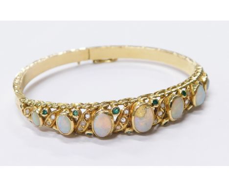 A Victorian opal hinged bangle, the design set with seven graduated oval opals and tiny diamond twist borders with outer emer