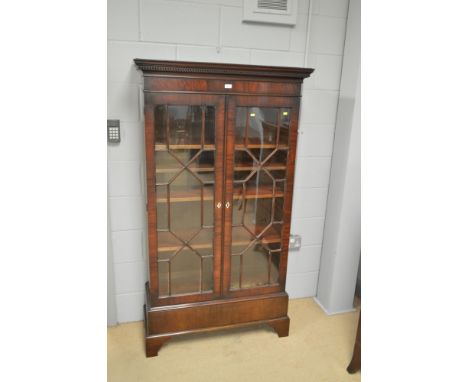 A 19th Century mahogany bookcase with projecting cornice, above a pair of astragal glazed doors with ivory escutcheons, the b