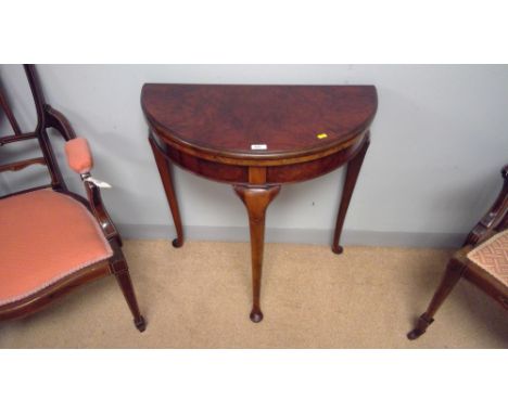 A 20th Century burr amboyna demi-lune card table, the hinged top enclosing a baize-lined playing surface, raised on slender c