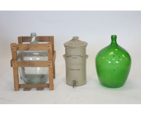 Two large glass bottles, one green, one clear in wooden cradle; and a ceramic water filter by The London Filter &amp; Pump Co