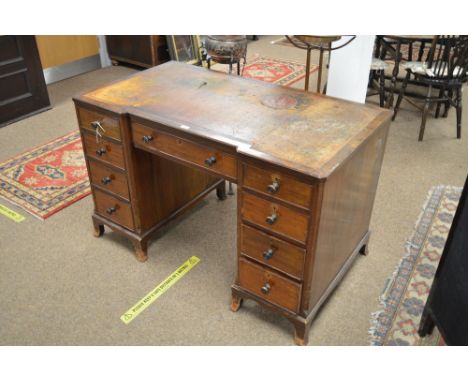 A mid 20th Century mahogany desk, with inverted breakfront top and inset writing surface above a central drawer flanked by tw