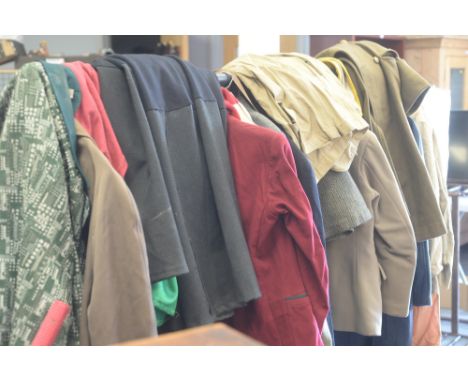 A rack of vintage clothing, to include: Military overcoats; tweed jackets; linen shirts; scarves; a suit carrier; and other v