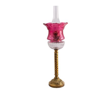 An Edwardian brass table oil lamp, early 20th century; the burner above a lobed reservoir and a repousse wrythen shaft to a f