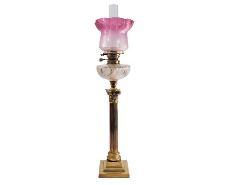 A late Victorian or Edwardian brass and glass mounted columnar table oil lamp, circa 1900; with crimped and etched cranberry 