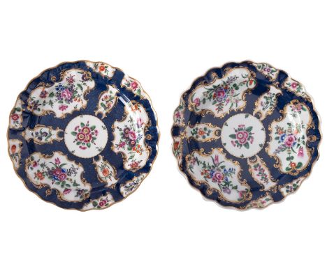 A pair of First Period Worcester plates with fluted rims, painted with flower sprays within gilt cartouches reserved on a sca