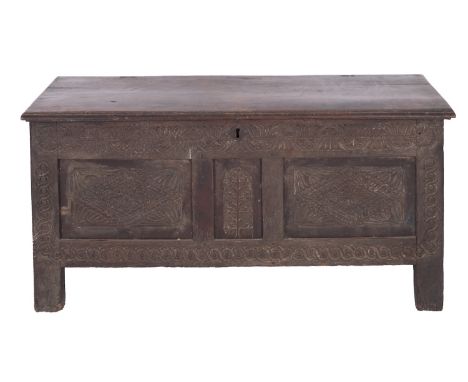 A Jacobean oak coffer, circa 1680; the hinged cover with moulded edges; above a stylised relief carved frieze, the central Tr