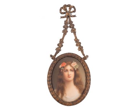 A Continental porcelain oval plaque painted with a head and shoulders portrait of a girl with flowers in her hair, 8cm high, 