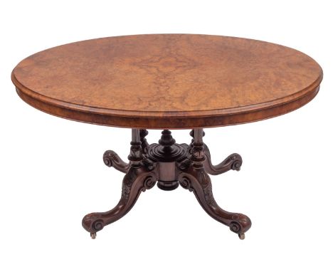 A Victorian walnut oval centre table, circa 1865; the quarter veneered flip top with moulded edges; the block on four knop tu