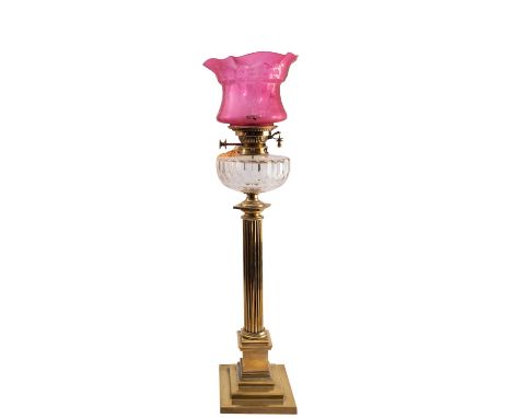 A late Victorian or Edwardian brass and glass mounted columnar table oil lamp, circa 1900; with crimped and etched cranberry 