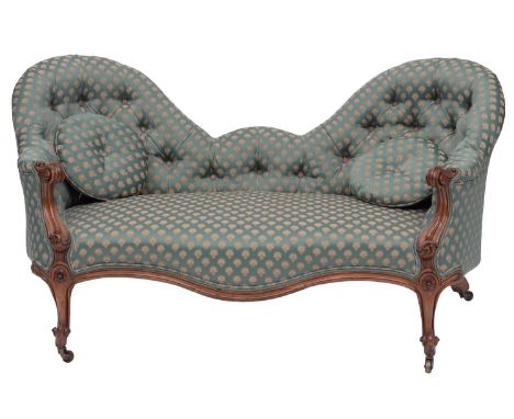 A Victorian carved walnut and upholstered conversation sofa, circa 1870; with later woven green coverings to the twin arched 