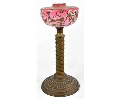 A Victorian brass oil lamp with detachable cranberry glass reservoir painted in enamels with floral detail on a barley twist 