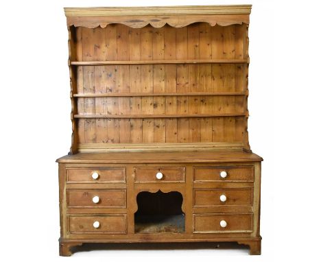A Victorian and later pine country kitchen dresser, with three tier plate rack top above an arrangement of seven drawers arou