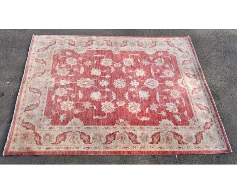 A Persian wool rug decorated with an all over floral design against a pale red ground, 230 x 170cm.Condition Report: All over