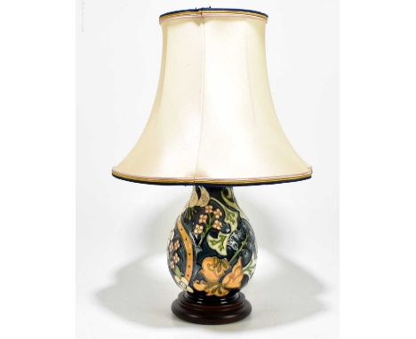 MOORCROFT; a table lamp decorated with flowers against a blue/green ground, on turned wood base, with shade, overall height 4