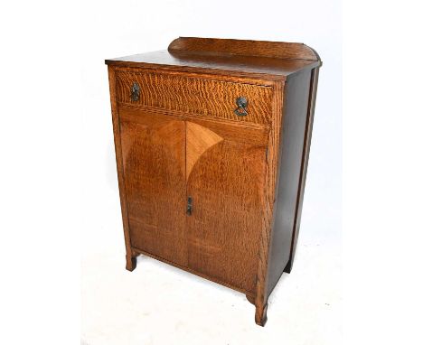 A late Art Deco oak cabinet, with single door above two cupboard doors with arched inlaid panels, on outswept legs, height 11