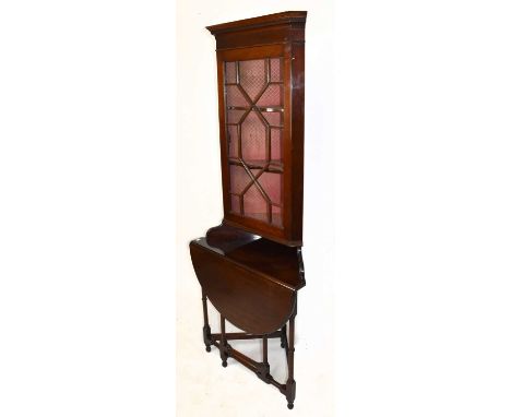 An early 20th century mahogany freestanding corner cabinet with moulded cornice above the astragal glazed door and drop-leaf 