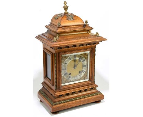 A late 19th century German walnut mantel clock with gilt metal urn finial and applied detail, the brass face set with silvere