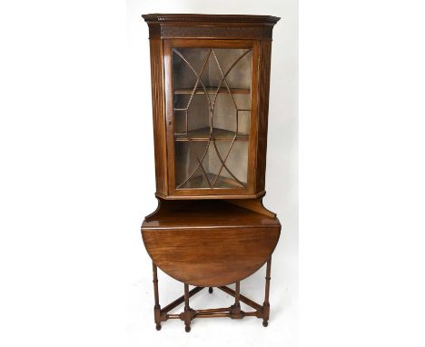 An early 20th century mahogany freestanding corner cabinet with moulded cornice and blind fret decoration above the single as