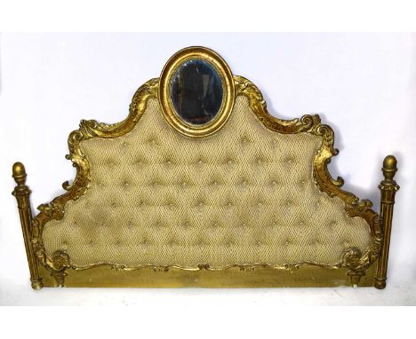 A reproduction gilt French headboard, the oval mirror with scrolling arms above the button backed gilt and ivory geometric ma