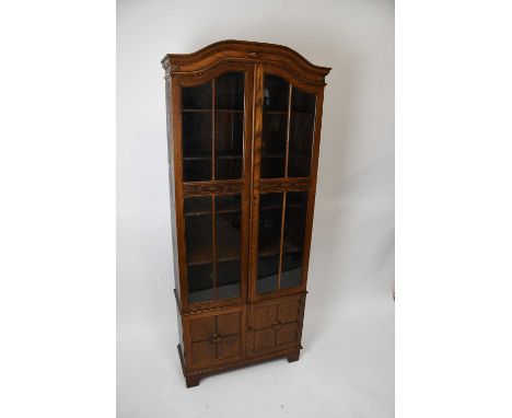 A 1920s oak two door display cabinet, with two glazed doors above two panelled doors, on bracket feet, height 192cm, width 80